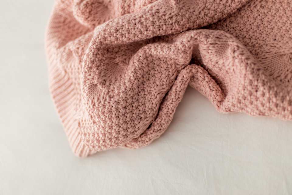close up of peach colored knit throw on white countertop